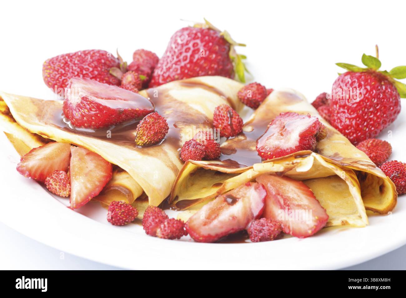 Frittelle con differenti le fragole con lo sciroppo di cioccolato su bianco Foto Stock