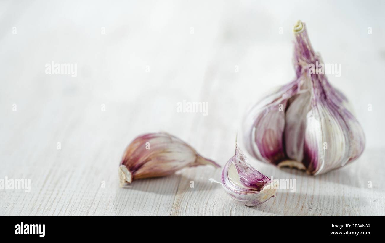 Bulbo d'aglio con spicchi d'aglio su sfondo bianco di legno. Perfetto aglio con spazio per copiare testo o design. Orizzontale Foto Stock
