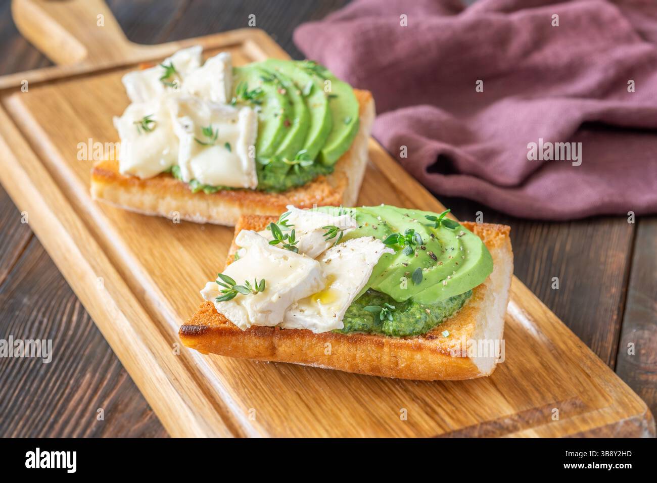 Panini tostati con ciabatta a strati di brie, avocado e spinaci cremosi, erbe aromatiche delicate Foto Stock
