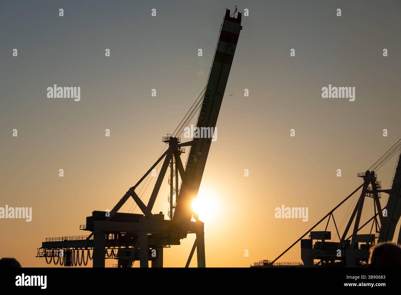 Amburgo, Germania - 27 aprile 2025: Gru portacontainer nel porto di Amburgo al tramonto presso il terminal di Tollerort, sagomata contro l'Elba, simbolo di gestione portuale commerciale, logistica e industriale *** Containerkran im Hamburger Hafen am Terminal Tollerort bei Sonnenuntergang, silhouette vor der Elbe, ein Symbol für Handel, Logistik und industrielle Hafenwirtschaft Foto Stock