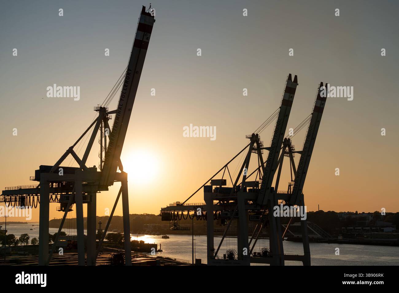 Amburgo, Germania - 27 aprile 2025: Gru portacontainer nel porto di Amburgo al tramonto presso il terminal di Tollerort, sagomate contro l'Elba, simbolo di gestione portuale commerciale, logistica e industriale *** Containerkräne im Hamburger Hafen am Terminal Tollerort bei Sonnenuntergang, silhouette vor der Elbe, ein Symbol für Handel, Logistik und industrielle Hafenwirtschaft Foto Stock