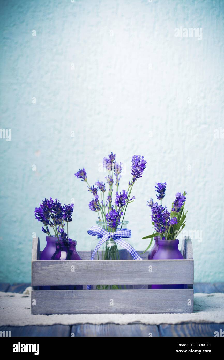 Lavanda in bottiglia, stile provance decor, scatola in legno su tovaglia a crochet Foto Stock