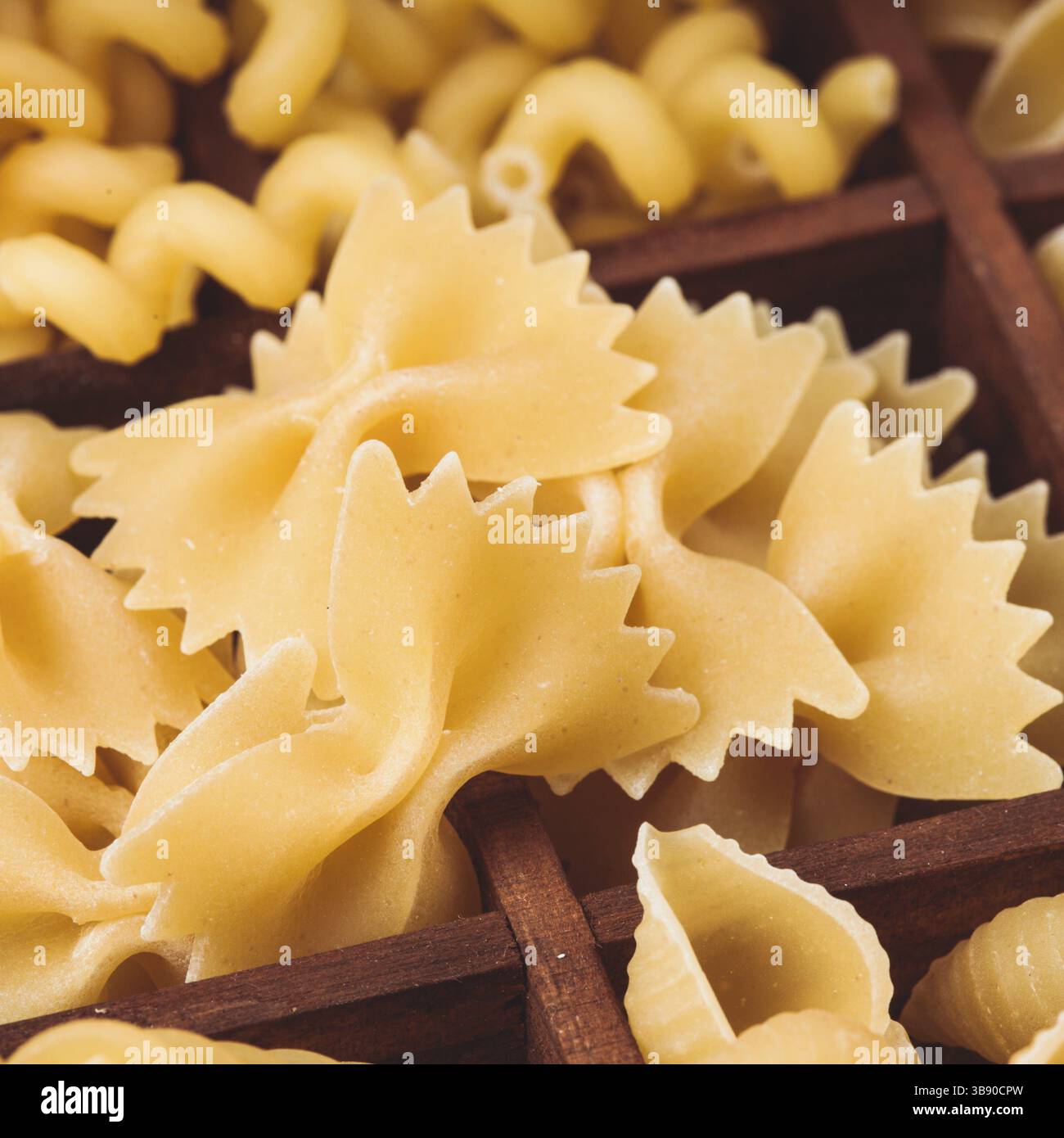 Vari tipi di pasta nella scatola di legno sul tavolo. Chiudete farfalle Foto Stock