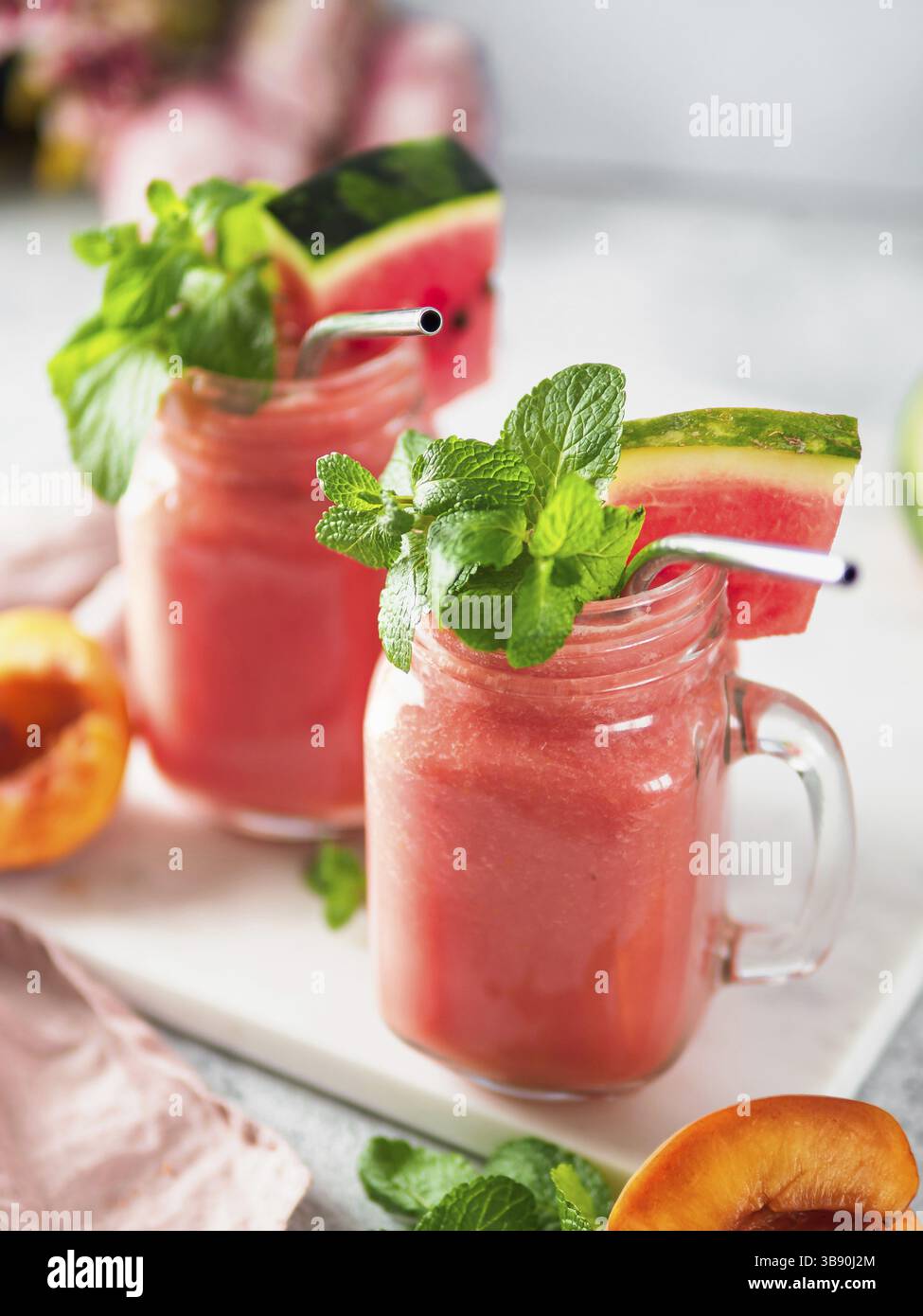 Frullati di anguria e pesca appena miscelati in barattolo mason e paglia metallica. Spazio di copia per testo o progetto. Verticale Foto Stock