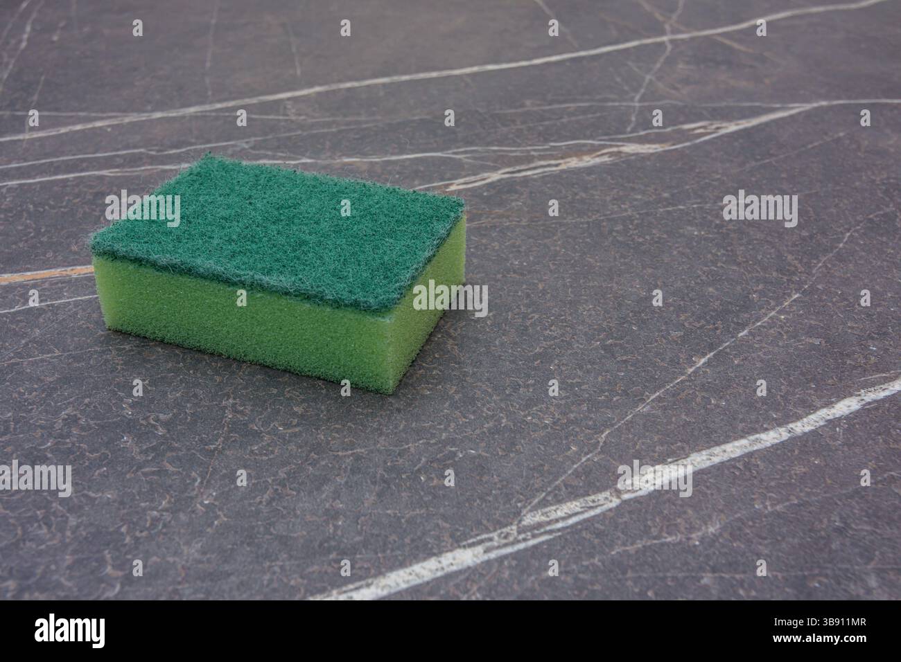 Una spugna verde per la pulizia su un piano in marmo Foto Stock
