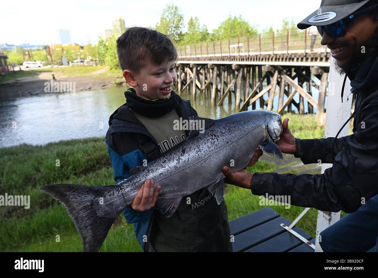 5 giugno 2023: Bradly Reed, di nove anni, prende una mano da Nate Hall del Bait Shack mentre regge un salmone reale da 17,45 libbre catturato durante una marea in arrivo a Ship Creek vicino al centro di Anchorage, Alaska, lunedì mattina, 5 giugno 2023. (Immagine di credito: © Bill Roth/Anchorage Daily News via ZUMA Press Wire) Foto Stock