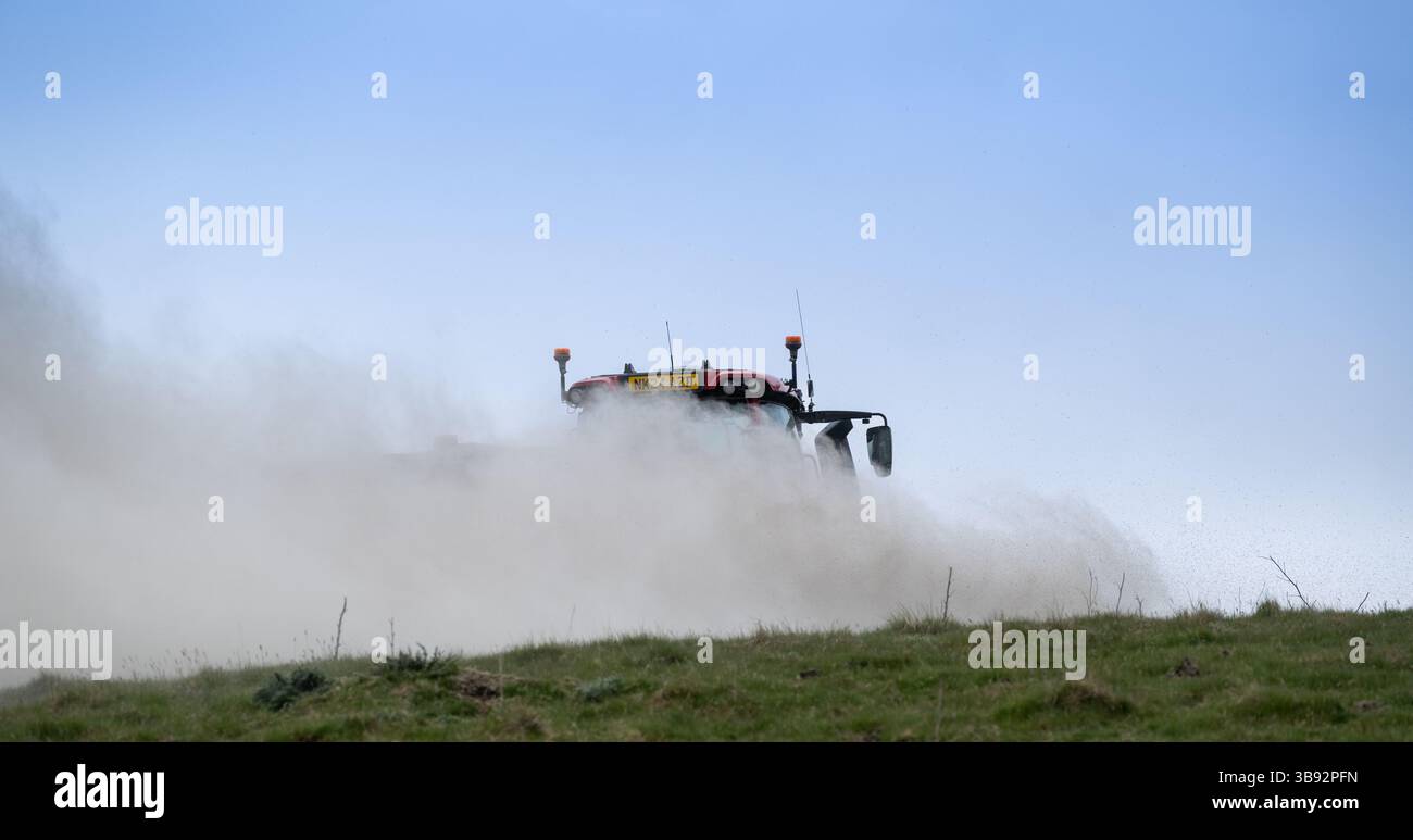 Appaltatore agricolo, alla guida di un trattore Valtra rosso, spalmando calce su un ripido pascolo per migliorare il pH del terreno e la qualità del terreno. Wensley Foto Stock