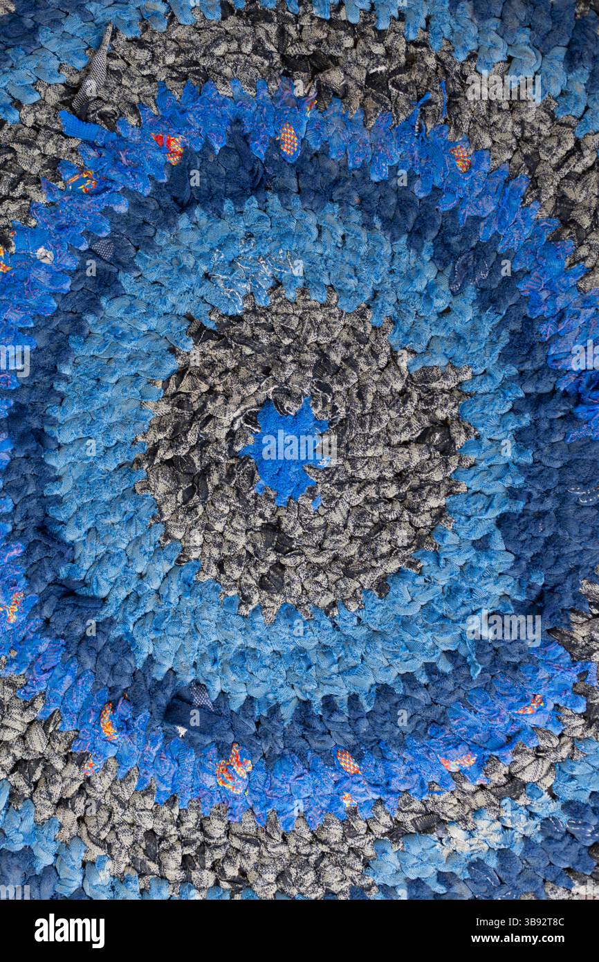 Primo piano del tappeto in tessuto riciclato realizzato a mano: Struttura ecologica Boho Home decor. Tappeto in tessuto intrecciato colorato con cerchi concentrici in tonalità blu e grigio Foto Stock