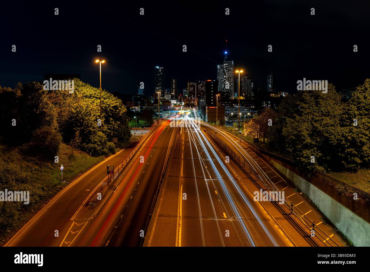 Lunga esposizione di percorsi leggeri per auto e dello skyline di Leeds di notte, creando una vivace scena urbana Foto Stock