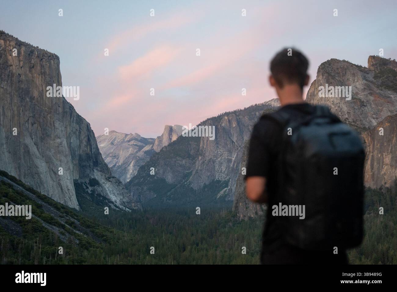 Uomo che guarda alla Yosemite Valley con una macchina fotografica che scatta foto del Parco Nazionale al tramonto. Foto Stock