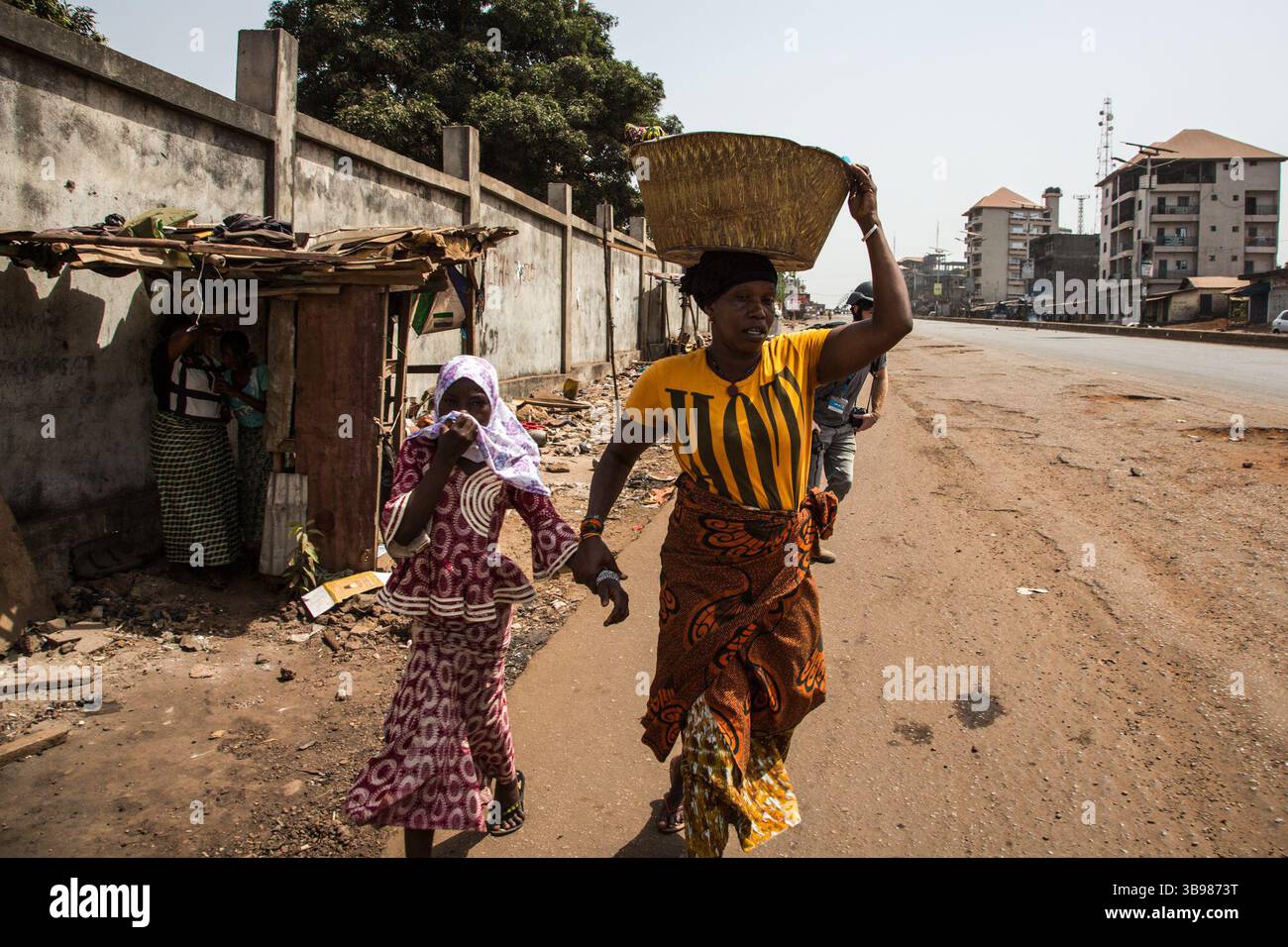 29 febbraio 2020, Conakry, Conakry, Guinea: Sorpreso dal gas lacrimogeno delle granate sparate dalla polizia, una madre e la sua famiglia fuggono dagli scontri... da metà ottobre, la capitale della Guinea vive al ritmo delle scene di guerriglia urbana tra giovani dimostranti del fronte Nazionale per la difesa della Costituzione e la polizia. Protestano contro la volontà del presidente Alpha Conde di candidarsi per un terzo mandato cambiando la Costituzione. Almeno trenta persone sono morte negli scontri dalla fine del 2019 (Credit Image: © Sadak Souici/ZUMA Press Wire) Foto Stock