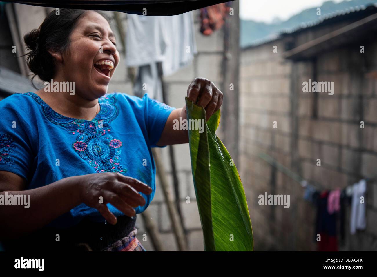 8 ottobre 2022, San Lucas Toliman, Guatemala: Una donna ride mentre lava le foglie di maxan per preparare Tamales a raccogliere fondi con l'obiettivo di costruire la chiesa evangelica "Gesù Cristo è la nostra bandiera", che è attualmente fatta di legno, con materiali più durevoli. Il tamale (dal nahuatl tamalli, che significa avvolto) è un cibo tradizionale guatemalteco di origine precolombiana, fatto di mais, ripieno di pollo e vari ingredienti, cucinato in un fascio di foglie vegetali. (Immagine di credito: © Mariana Nedelcu/ZUMA Press Wire) Foto Stock
