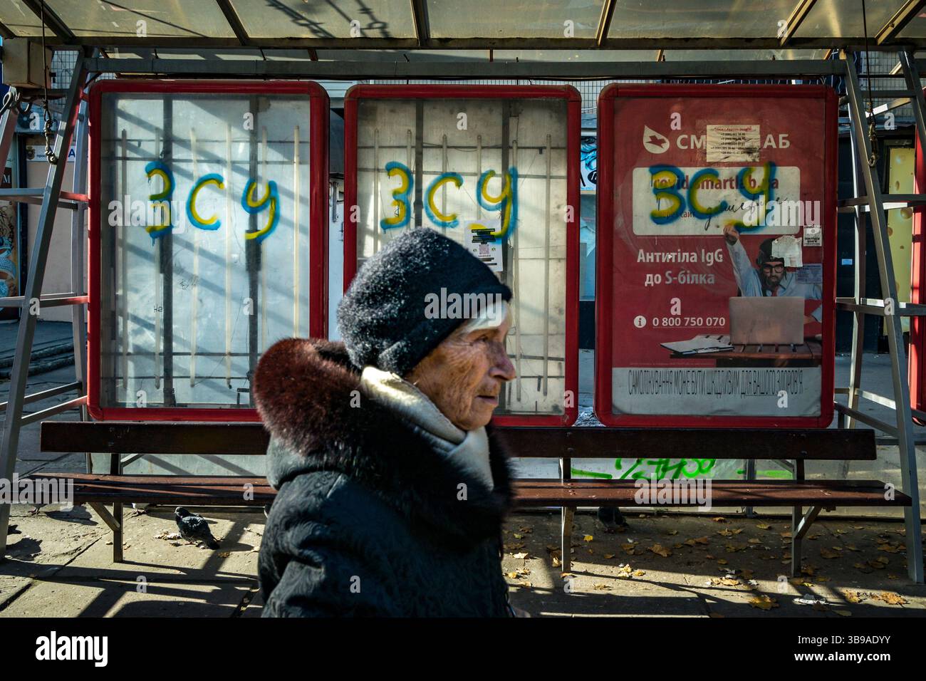 14 novembre 2022, Kherson, Ucraina: Una donna oascia sotto una fermata dell'autobus con il sostegno dell'esercito ucraino nella città di Kherson. Le 3 lettere significano forze armate ucraine. La città fu recuperata per l'Ucraina dal suo esercito dalle mani degli occupanti russi durante l'attuale invasione russa in Ucraina. (Immagine di credito: © Celestino Arce Lavin/ZUMA Press Wire) Foto Stock