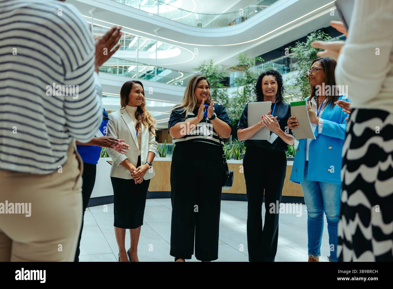 I professionisti in un ufficio moderno applaudono mentre tengono in mano i blocchi appunti. La scena cattura il lavoro di squadra, la collaborazione e il successo in un ambiente vivace e stimolante Foto Stock