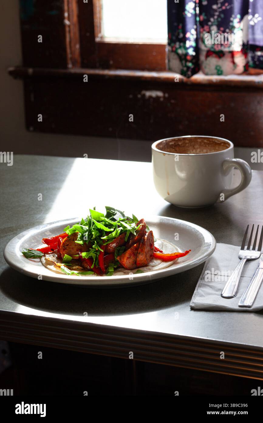 Piatto di salsiccia placcato con bevanda al caffè vicino alla finestra Foto Stock