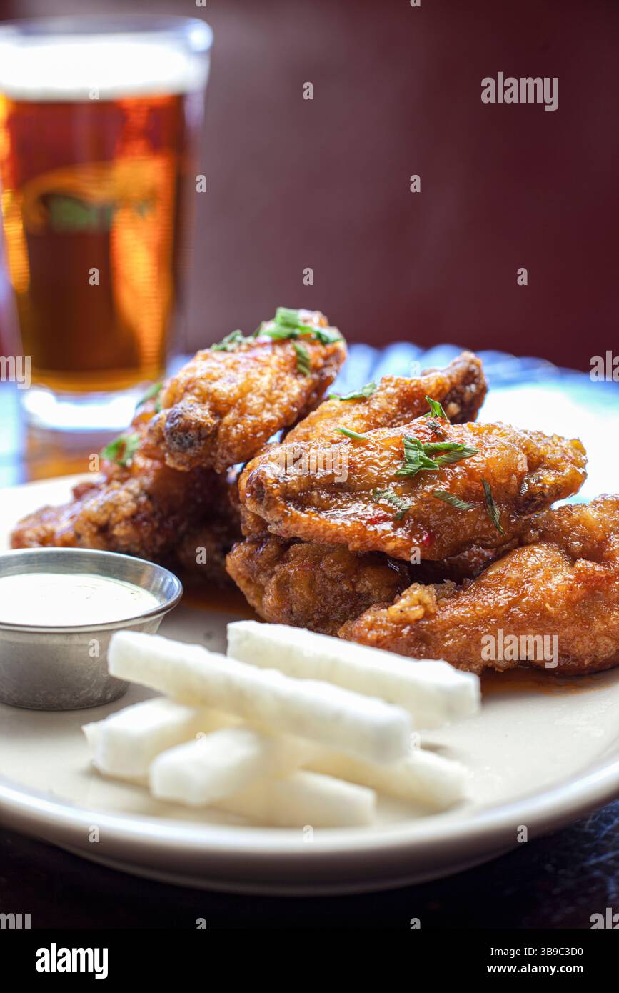Ali di pollo placcate soffocate in salsa con birra verticale Foto Stock