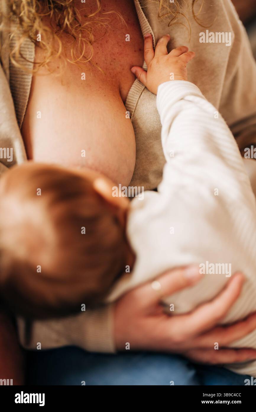 Primo piano del momento dell'allattamento mostrando la mano del bambino sui chicchi della madre Foto Stock