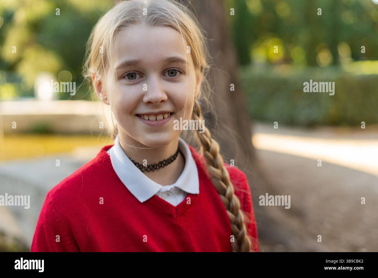 Una ragazza allegra che brilla di gioia in un bellissimo ambiente naturale che indossa un pullover rosso Foto Stock