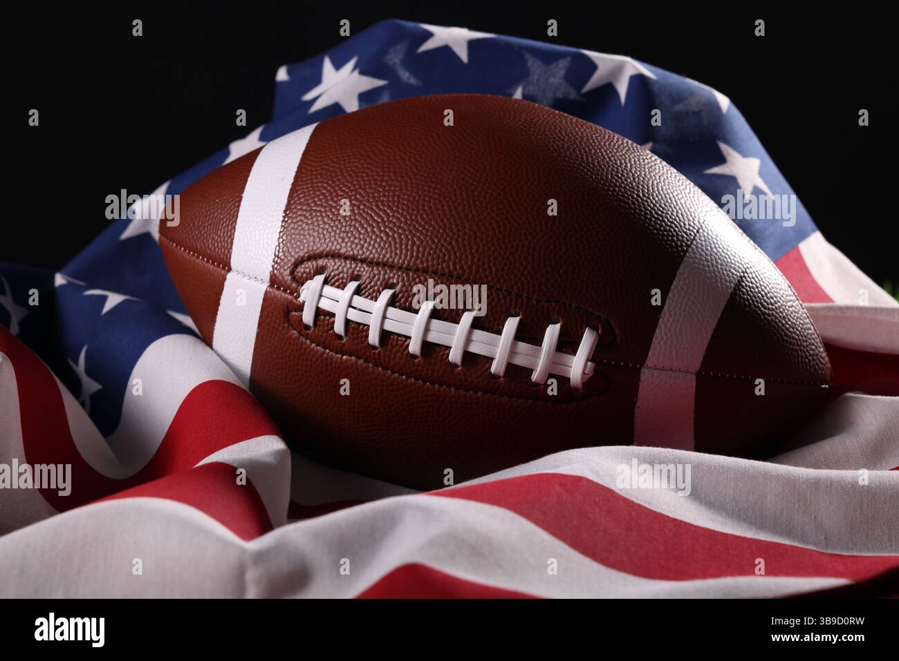 Pallone da football americano e bandiera USA. Gioco sportivo. Super Bowl negli Stati Uniti. Palla da calcio primo piano macro fotografia con spazio di copia. Foto di alta qualità Foto Stock