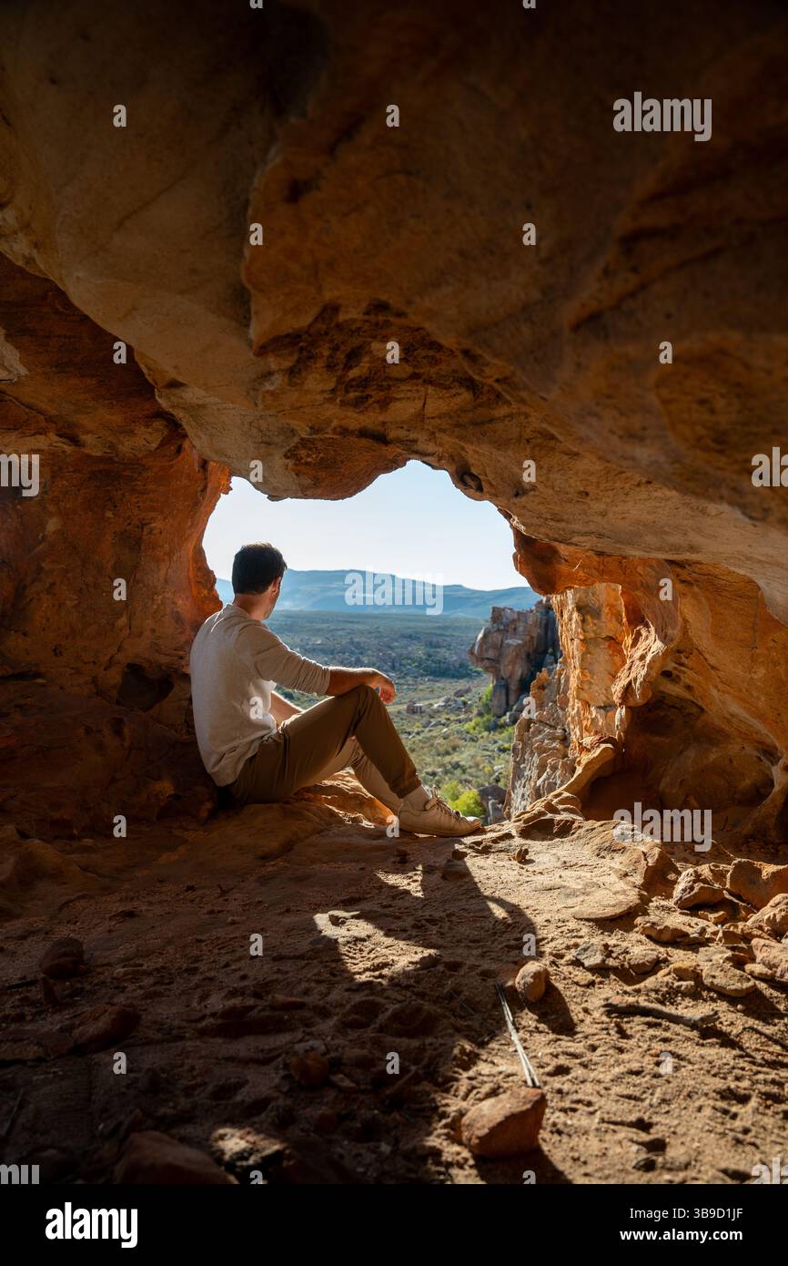Un escursionista seduto in una grotta aperta nella zona di Cederberg Wilderness, Sud Africa Foto Stock