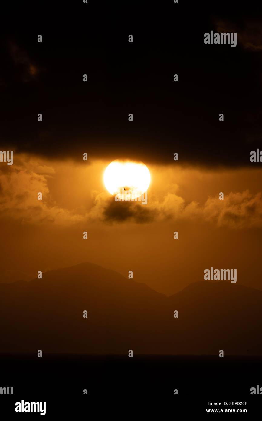 Un teleobiettivo mozzafiato del sole che tramonta dietro Table Mountain a città del Capo, Sud Africa. Foto Stock