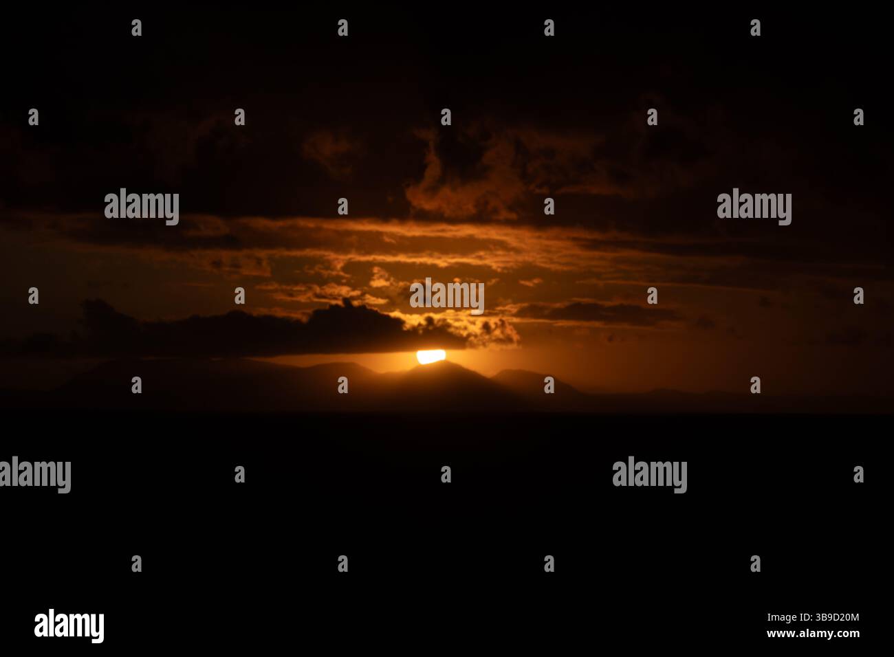 Un teleobiettivo mozzafiato del sole che tramonta dietro Table Mountain a città del Capo, Sud Africa. Foto Stock