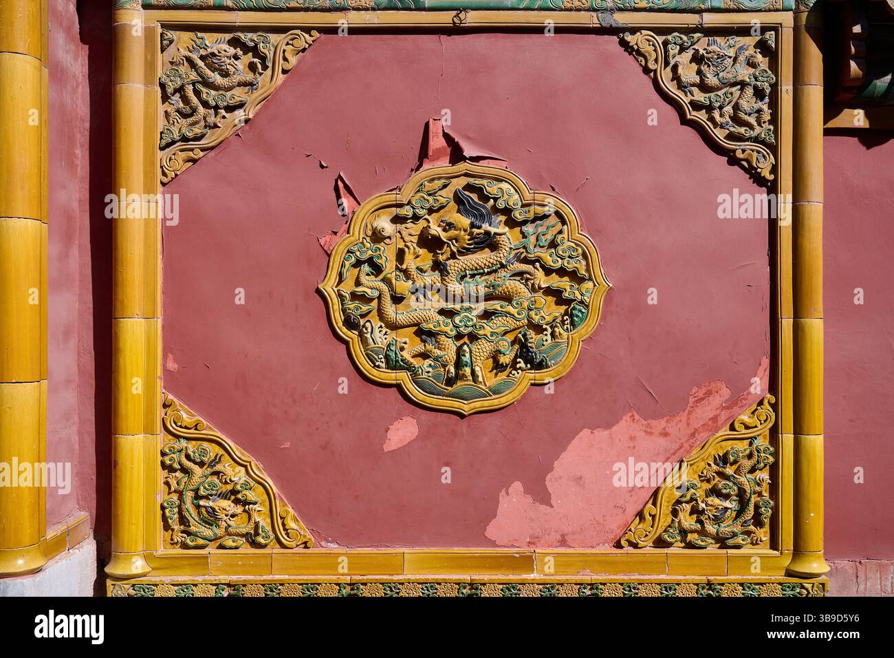 Dettagliato sollievo del drago cinese su un muro rosso nella città Proibita, evidenziando il simbolismo tradizionale Foto Stock
