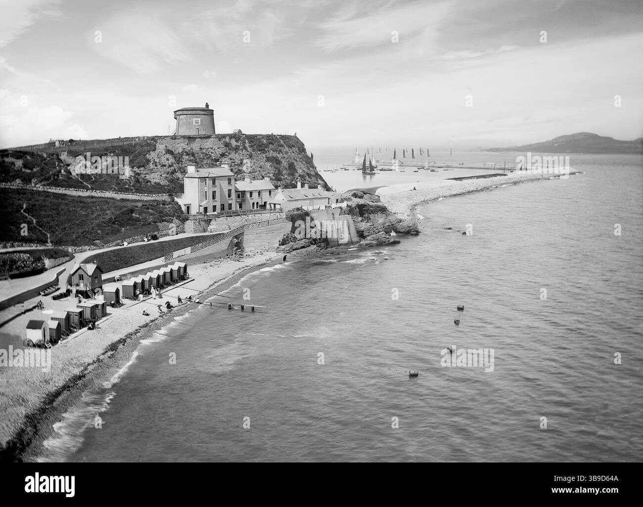 Una fotografia del tardo XIX secolo della Torre martello che si affaccia sul porto di Howth e sulla spiaggia di Balscaddan, uno dei luoghi preferiti per fare il bagno fiancheggiato da capanne in legno. Foto Stock