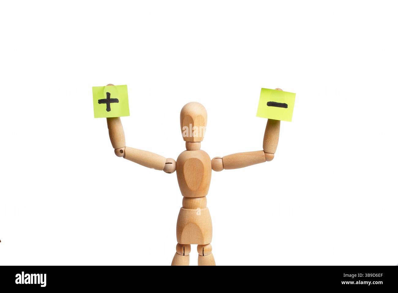 Un giocattolo di manichino di legno che regge carta adesiva con il segno meno e il segno più in mano su sfondo bianco Foto Stock