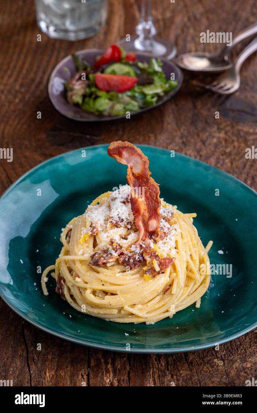 Spaghetti alla carbonara con insalata su legno Foto Stock
