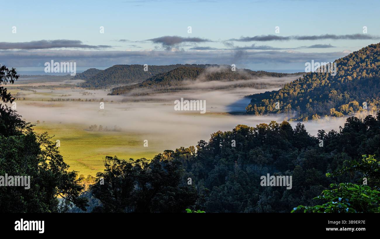 guardando in basso su una valle verde ricoperta di nebbia con isole di colline ricoperte di alberi al mattino presto nelle alpi meridionali della nuova zelanda Foto Stock