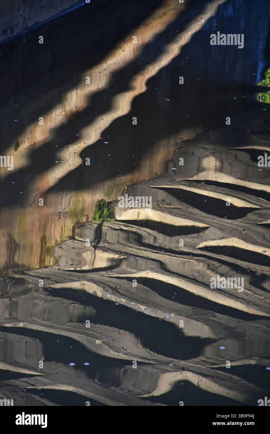 Effetti di luce e riflessi nell'acqua sotto un ponte Foto Stock