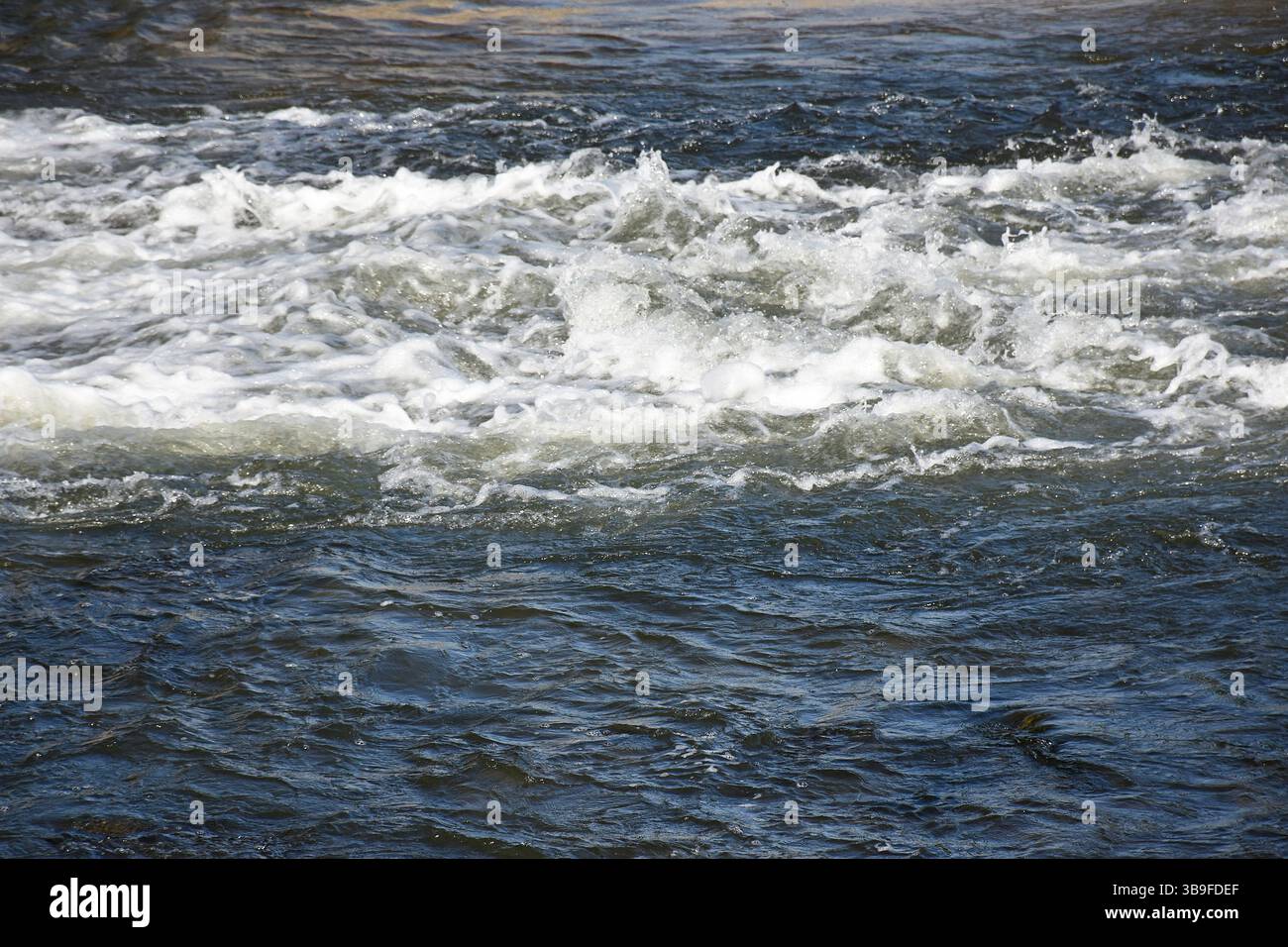 Schiumosità e spruzzi d'acqua del fiume dopo una diga Foto Stock