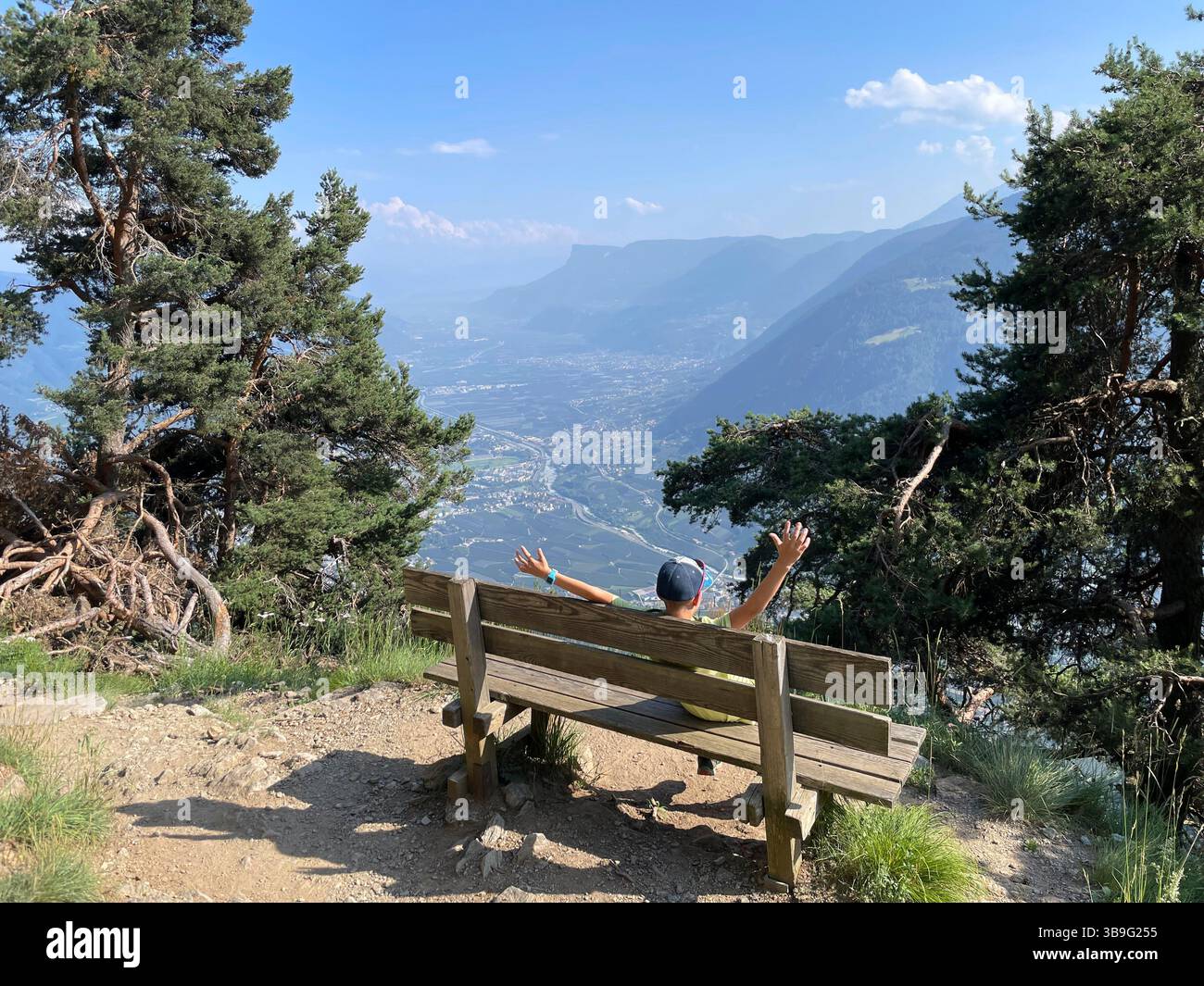 Escursione, escursione in montagna ai laghi Spronser, sosta per bambini su una panchina del sentiero escursionistico Leiteralm sopra Algund, vista sulla valle, natura, montagne, vista, picco di montagna, attività, sole, nuvole, cielo blu, parco naturale gruppo Texel, Merano, alto Adige, Italia Foto Stock