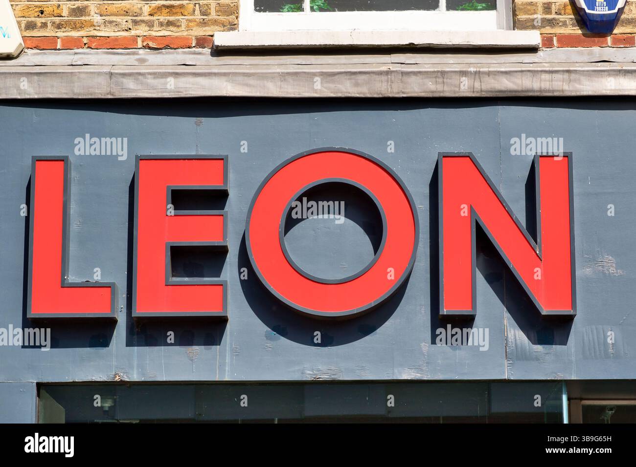 Foto ravvicinata della parola "LEON" in grandi lettere rosse e tridimensionali su sfondo grigio, montata su una facciata di un edificio a Kingston, Regno Unito. Foto Stock
