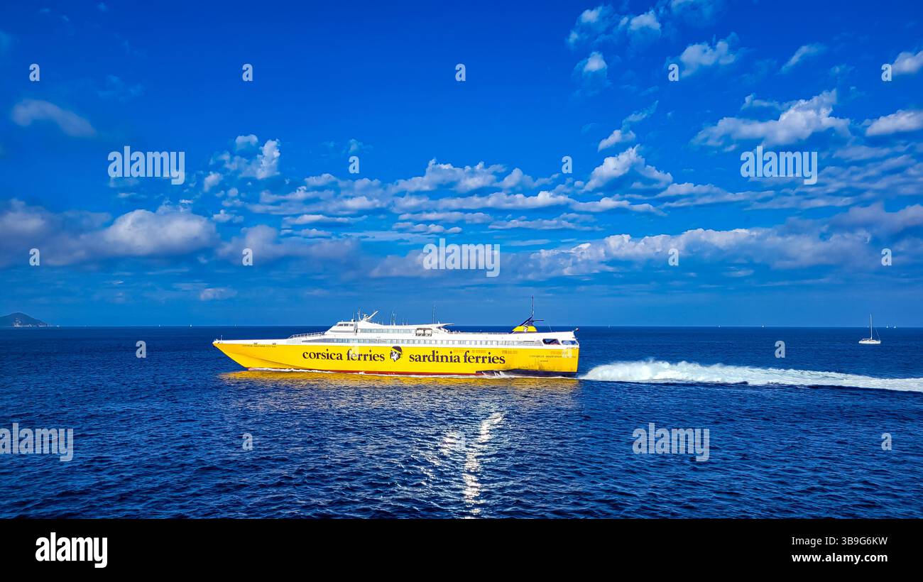 Traghetto giallo-bianco operato da Corsica Sardinia Ferries che va all'Isola d'Elba in una giornata di sole. In primo piano - un mare blu scuro, nella parte posteriore Foto Stock