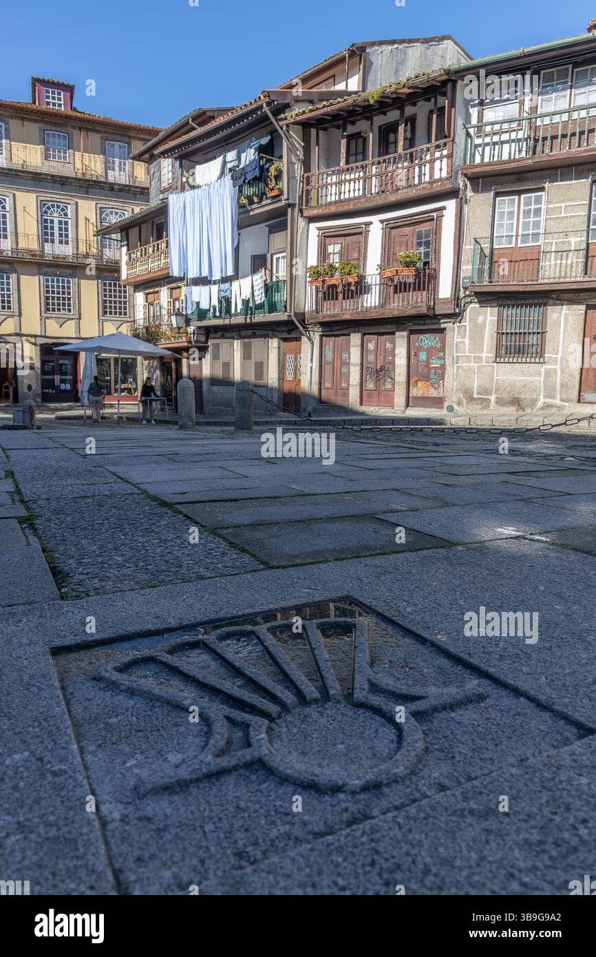 Vecchia piazza acciottolata con vecchie case sullo sfondo e lavanderia sul balcone, Braga, Guimaraes, Portogallo Foto Stock