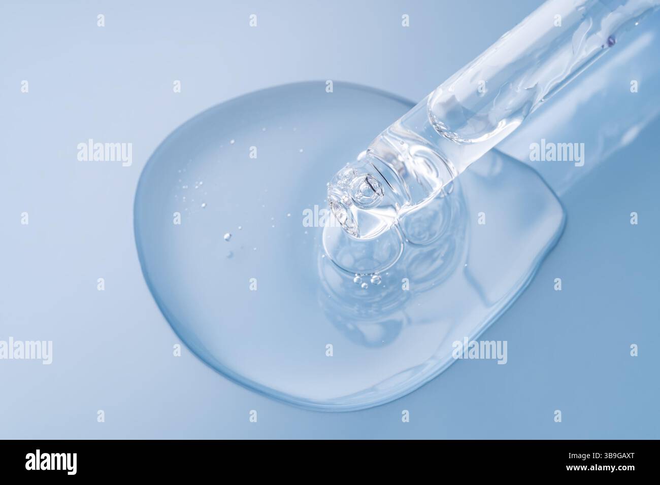 Primo piano di gocce di siero trasparente erogate da un contagocce su una superficie liscia e riflettente. Foto Stock
