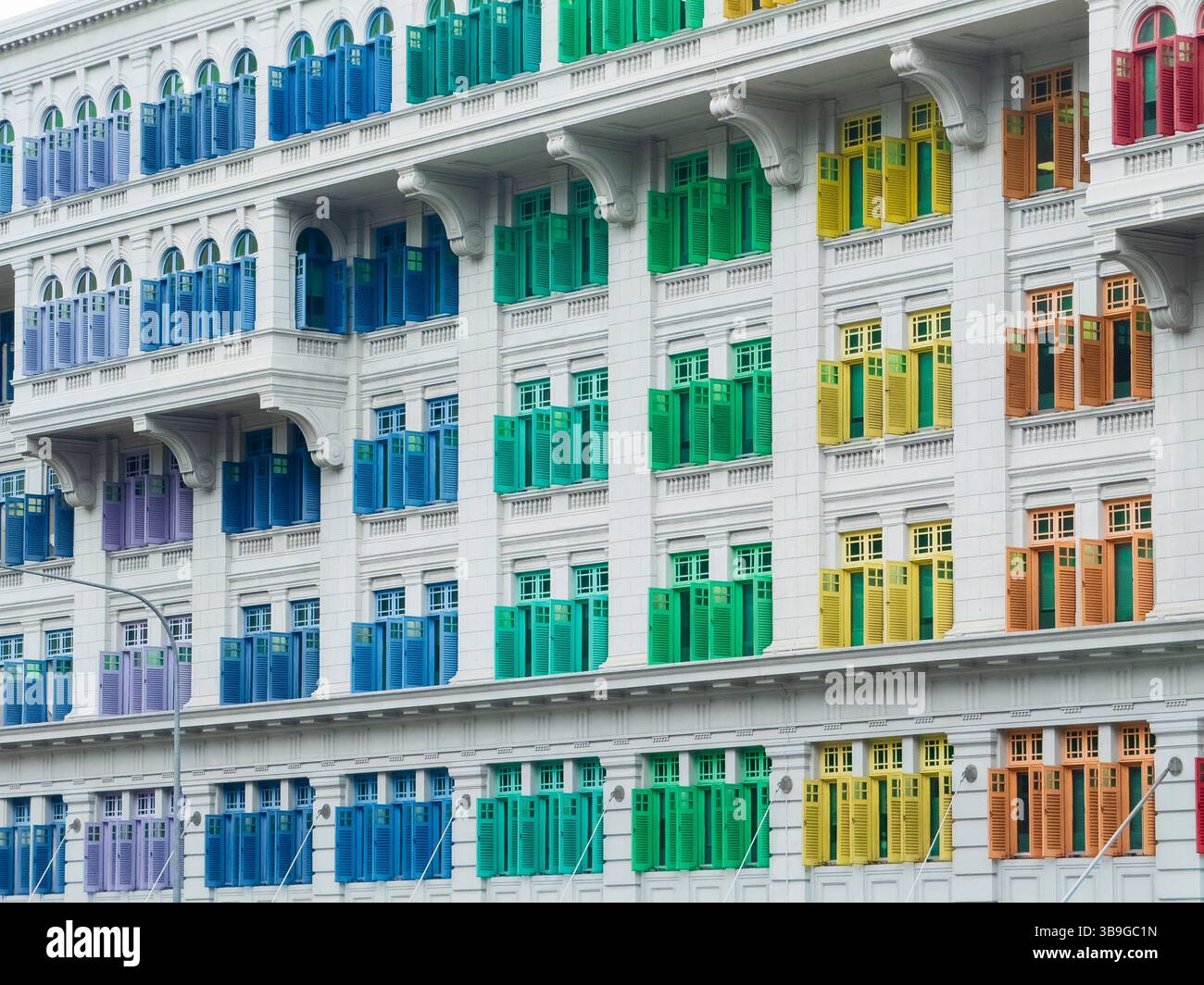 Una vibrante facciata di un edificio in stile coloniale a Singapore, che mostra una fila di persiane multicolori in uno schema simmetrico. Foto Stock