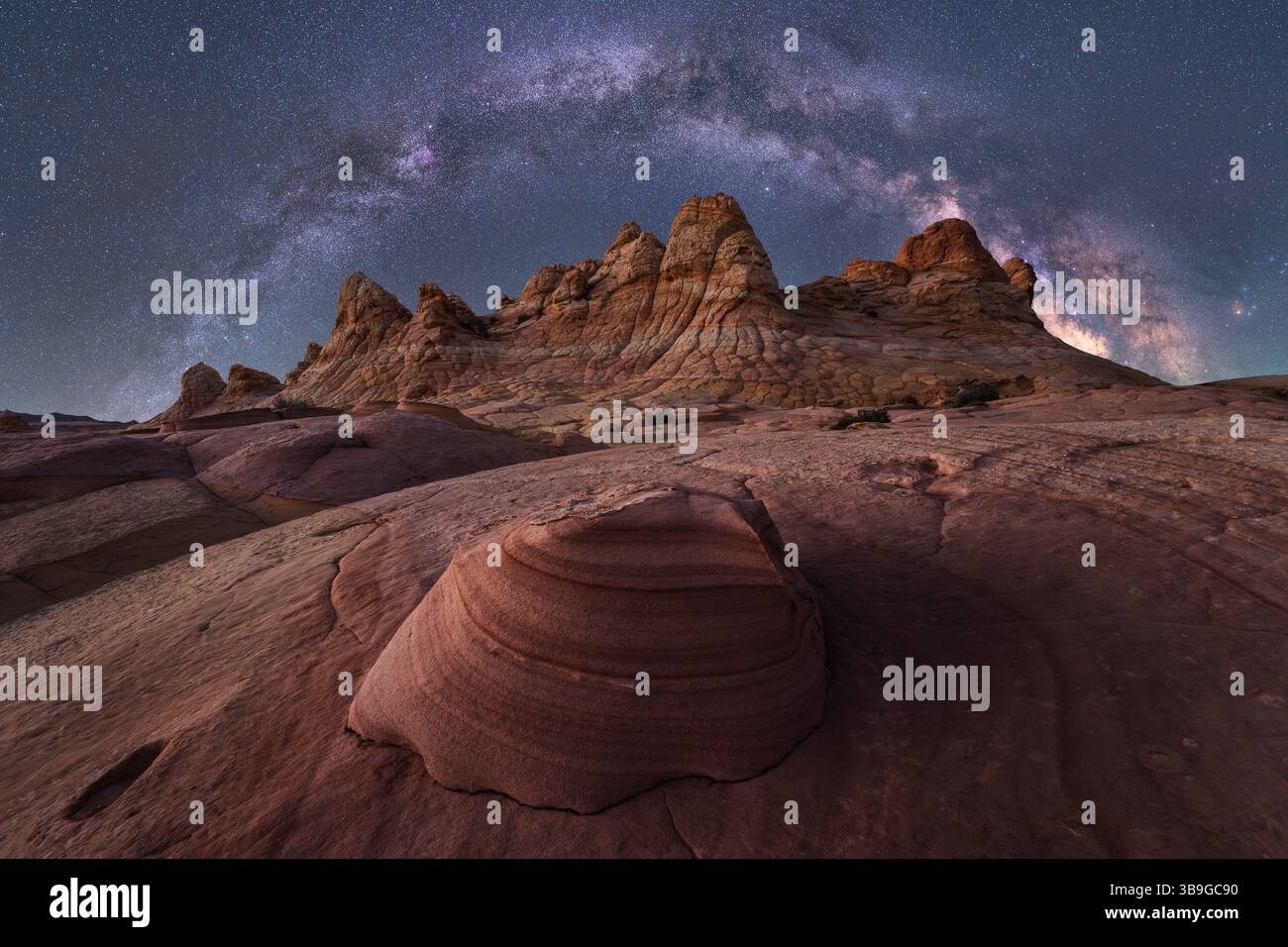 Una vista mozzafiato della via Lattea che illumina il cielo notturno sopra un aspro paesaggio desertico con impressionanti formazioni rocciose a Coyote Butte Foto Stock