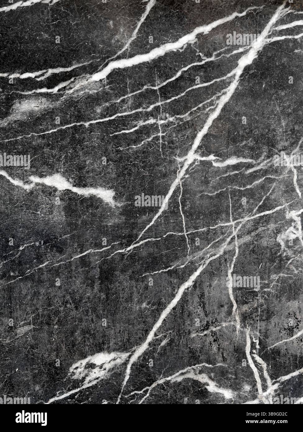 Primo piano di una superficie in marmo scuro con intricate venature bianche che la attraversano, che mostrano motivi e texture naturali ideali per sfondi, degni di nota Foto Stock