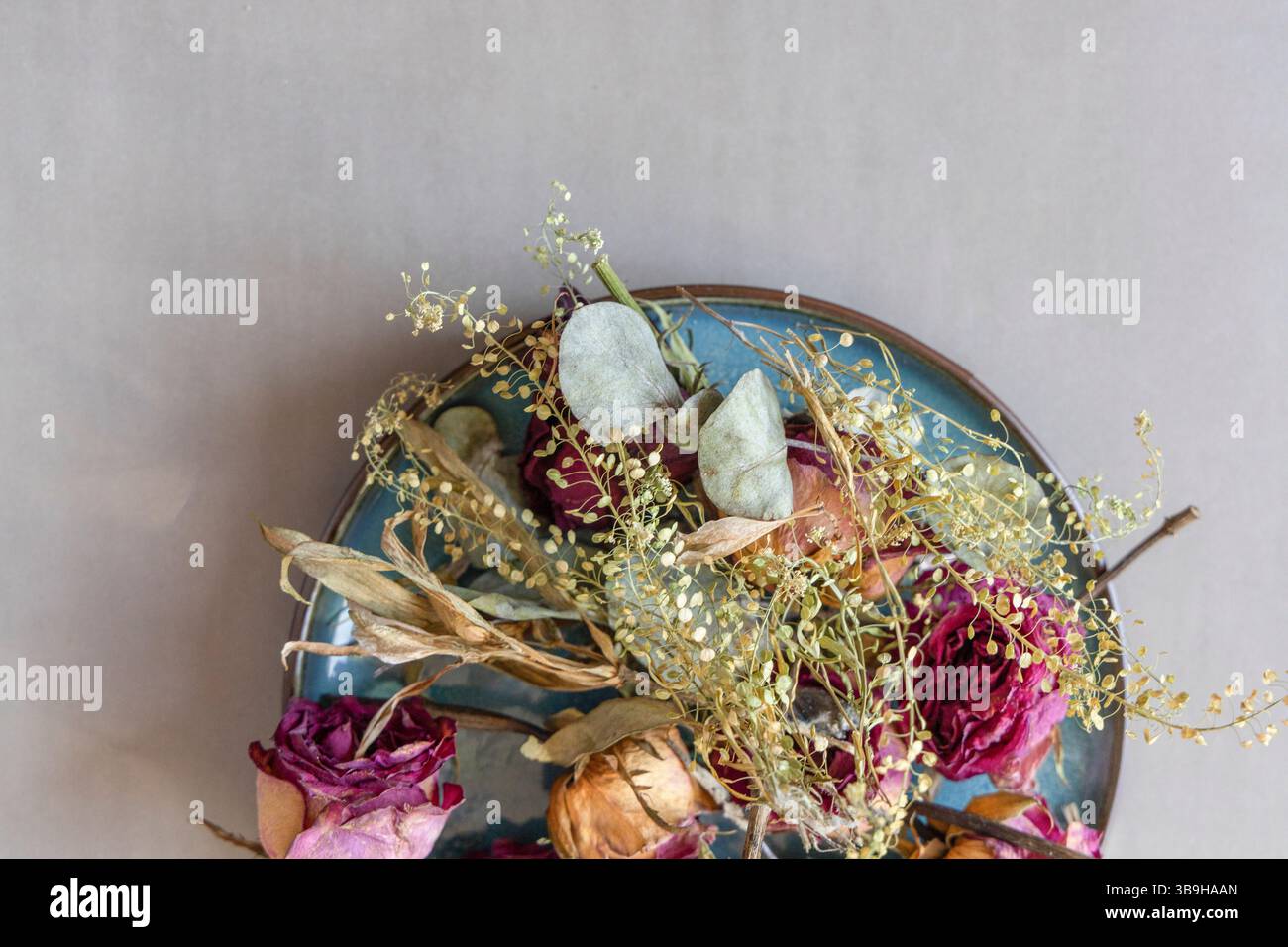 I petali di rosa essiccati si trovano come una colorata disposizione floreale su un piatto turchese Foto Stock
