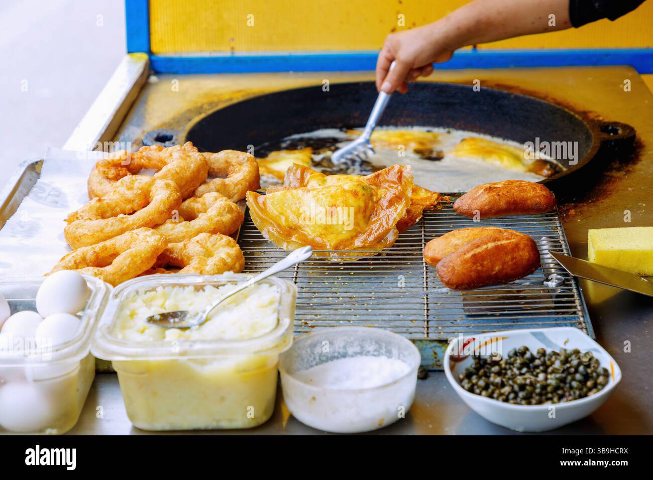 Preparazione di brik (gnocchi con purè di patate, capperi e uova) in una bancarella con bambalouni (riccioli di lievito) e fricassee (panini) ad Hammamet, Tunisia Foto Stock