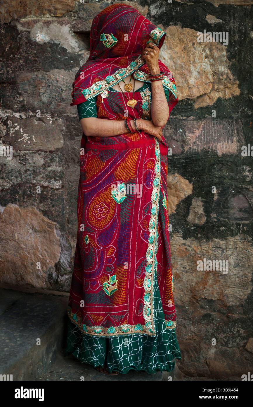 Donna misteriosa che indossa un sari rosso e nasconde il suo volto, a Ranthambore Fort, Rajasthan, India Foto Stock