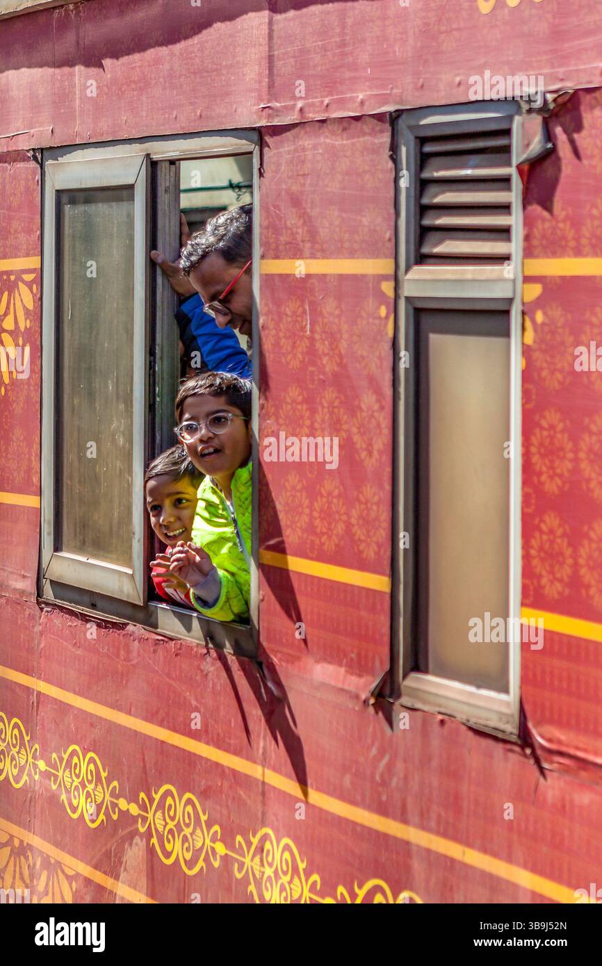 Padre con bambini eccitati che guardano fuori da un finestrino della carrozza del treno per Tara devi, vicino a Shimla, Himachal Pradesh, India Foto Stock