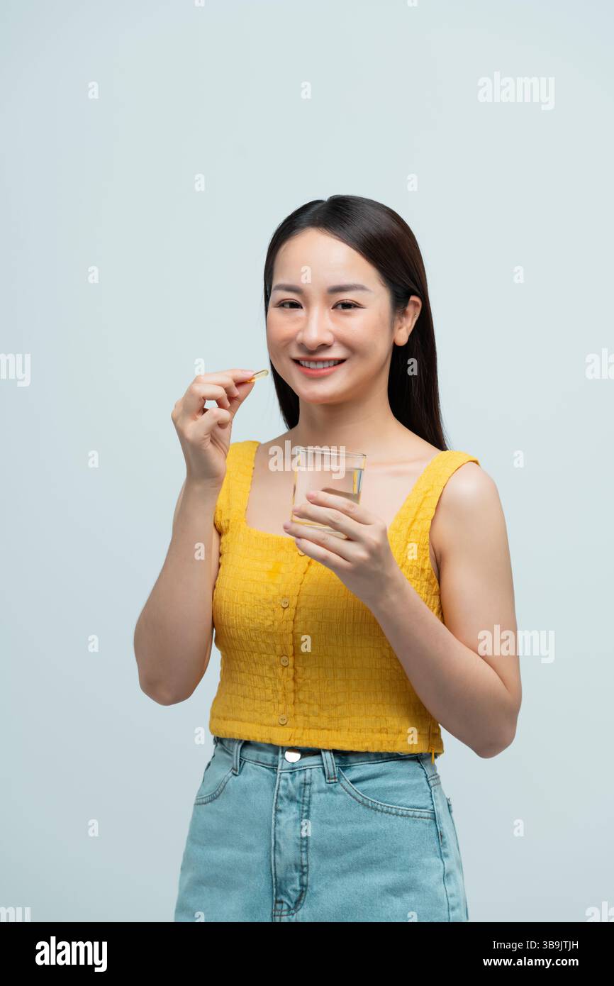 Donna che prende una pillola di vitamina con un bicchiere d'acqua Foto Stock