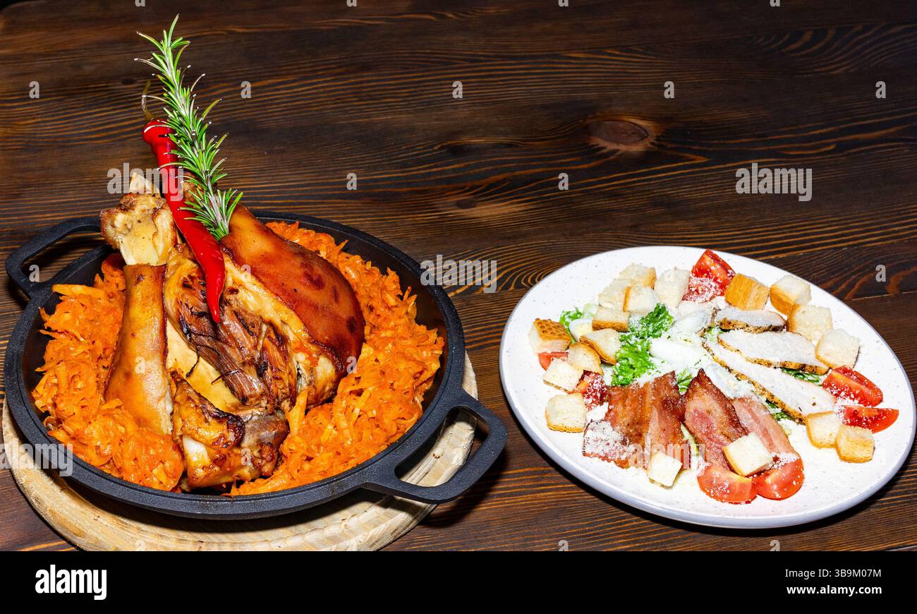 Una generosa porzione di carne arrostita viene servita su un letto di carote condite, accompagnata da un'insalata fresca con crostini e ingredienti a dadini, perfetto per te Foto Stock