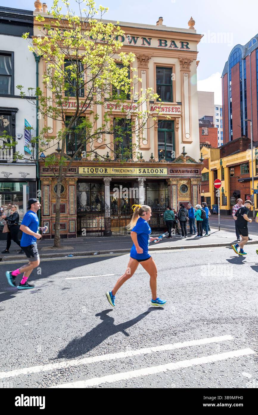 I corridori della maratona di Belfast corrono davanti al famoso Crown Bar di Belfast. Foto Stock