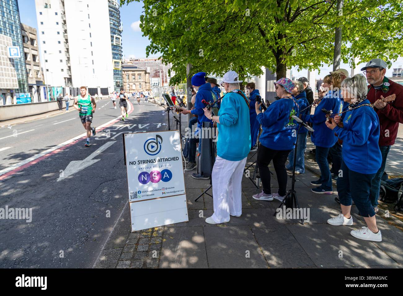 La band amatoriale Ukelele "No Strings Attached" si esibisce per i corridori e la folla alla maratona di Belfast. Foto Stock La band amatoriale Ukelele "No Strings Attached" si esibisce per i corridori e la folla alla maratona di Belfast. Foto Stock