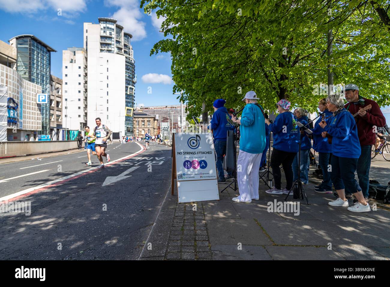 La band amatoriale Ukelele "No Strings Attached" si esibisce per i corridori e la folla alla maratona di Belfast. Foto Stock La band amatoriale Ukelele "No Strings Attached" si esibisce per i corridori e la folla alla maratona di Belfast. Foto Stock